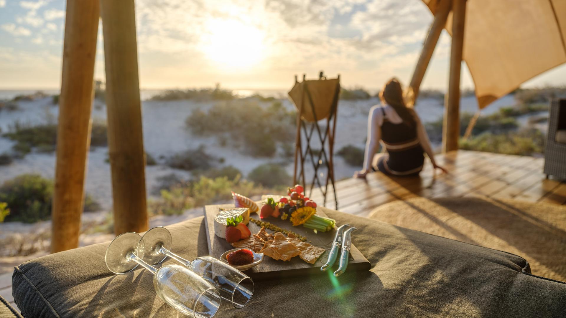 cheeseboard with champagne with person watching sunset