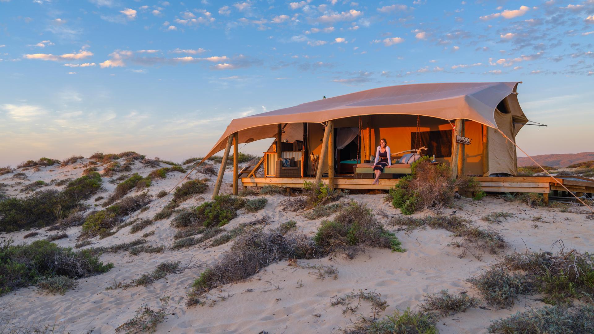 person sitting at glamping tent at sunset