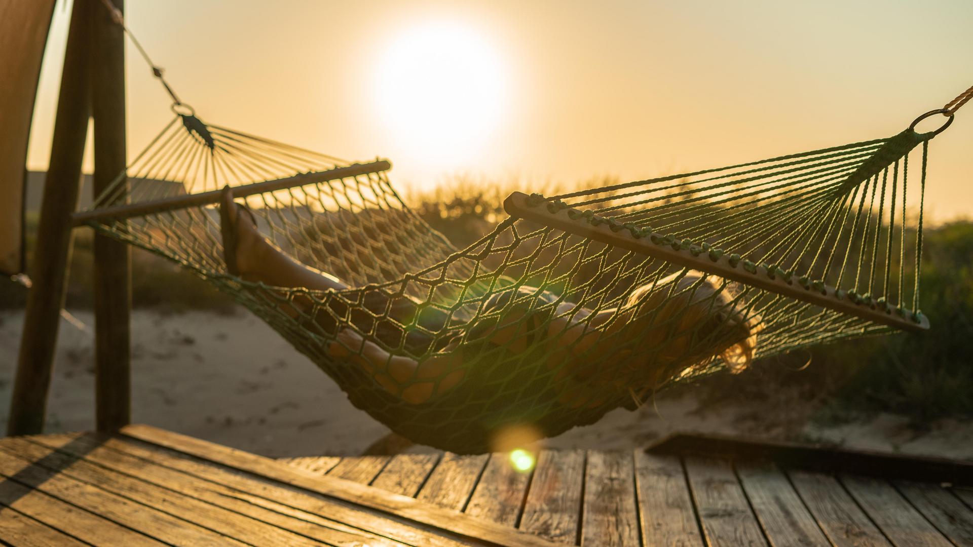 person in hammock at sunset